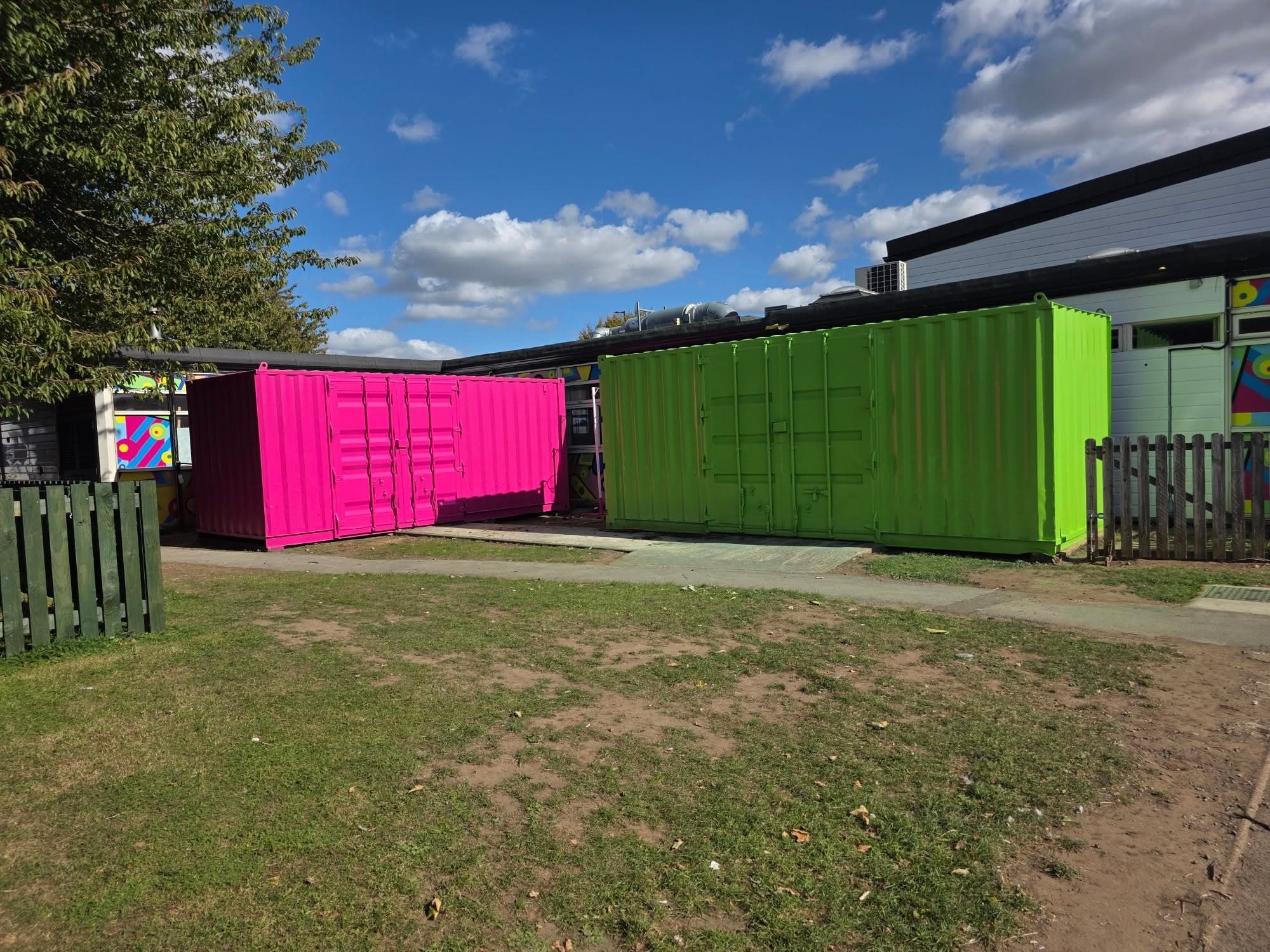 Two shipping containers after respraying, one bright pink and one lime green